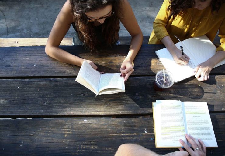 A group of people sitting at a table reading books.