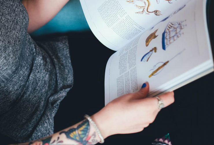 A person with tattoos is reading a book.