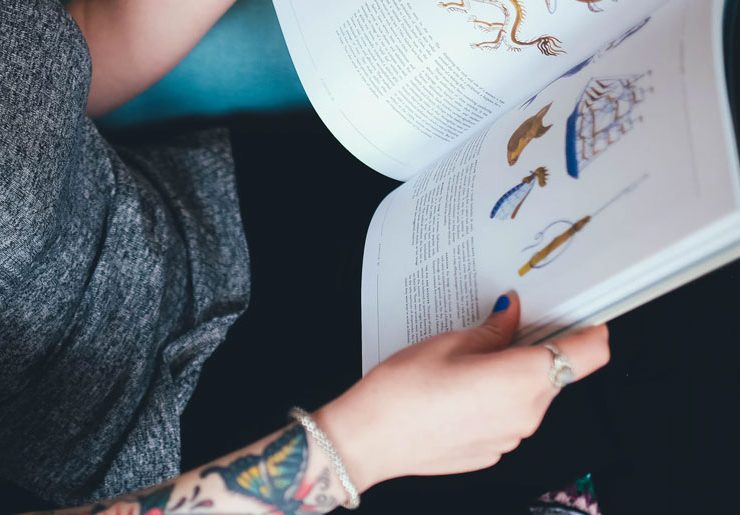 A person with tattoos is reading a book.