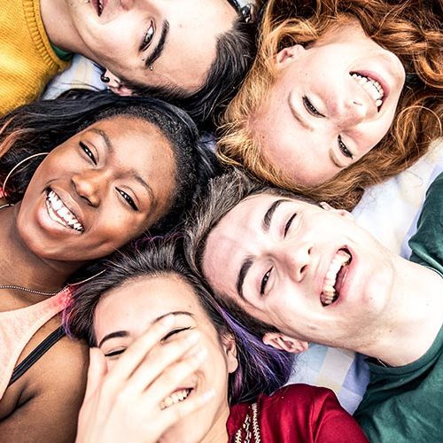 A group of people laying on the ground with their heads together.