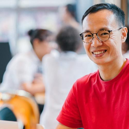 A man in red shirt smiling for the camera.