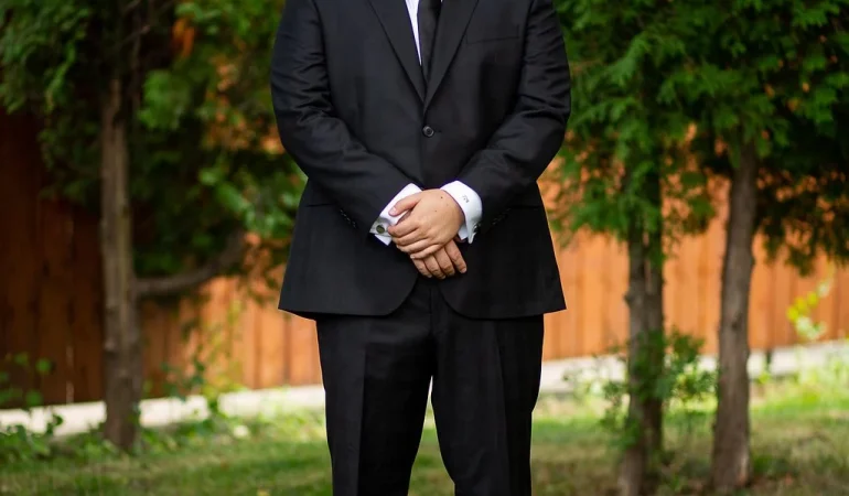 A man in a suit standing on the grass.