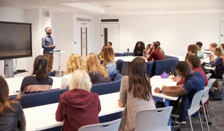A speaker addressing an attentive audience in a modern classroom.